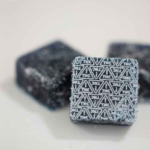 dark blue gummies with white THC ! triangle symbols imprinted on them