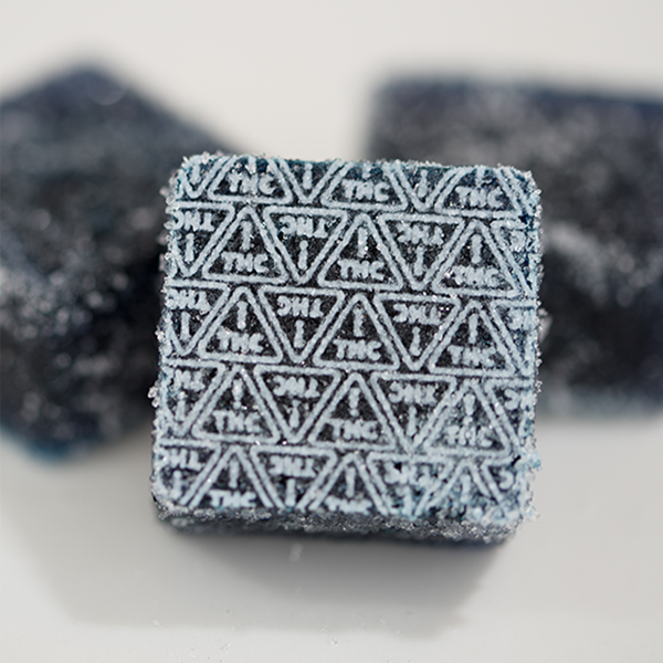 dark blue gummies with white THC ! triangle symbols imprinted on them