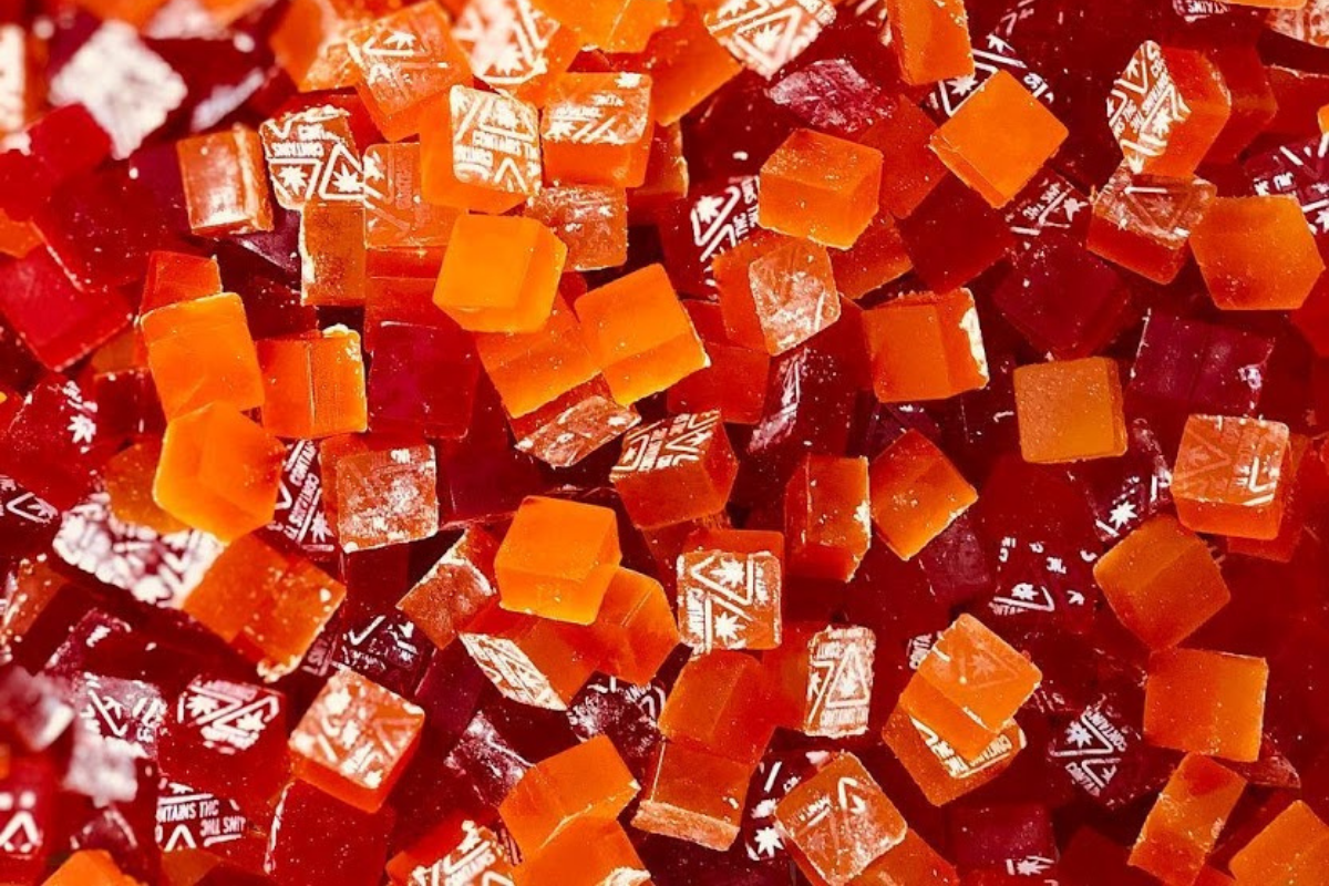 red and orange gummy cubes with white contains thc symbols on top